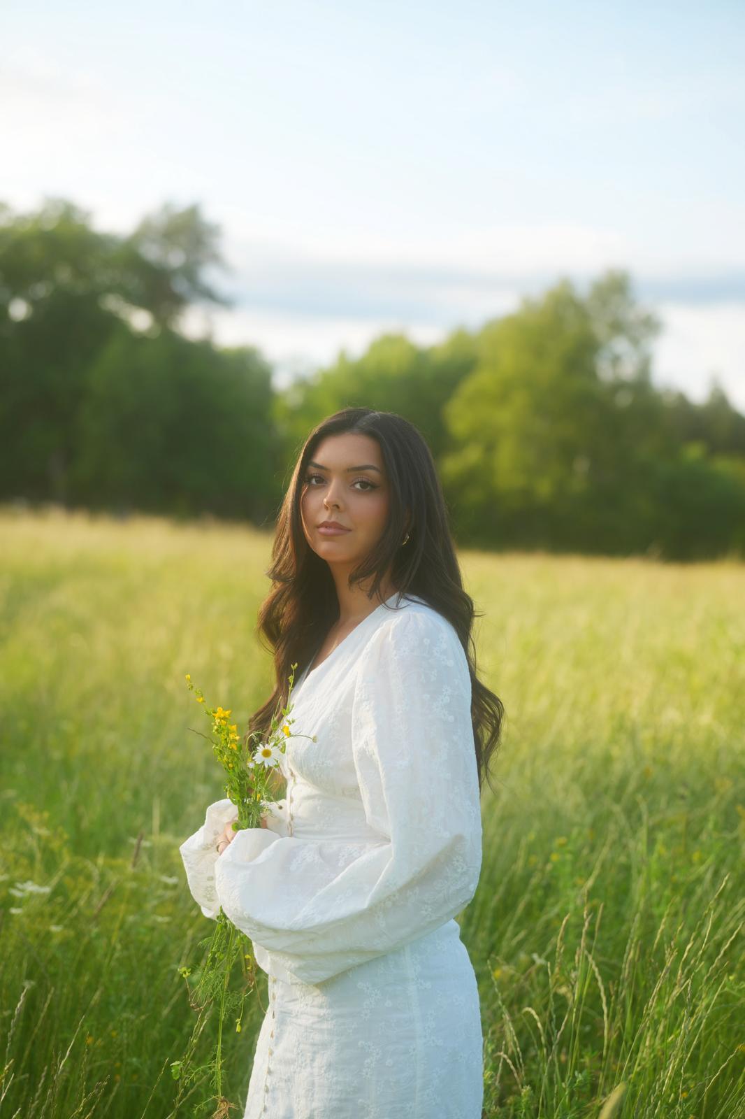 Victoria Grace holding wildflowers in a Swedish meadow